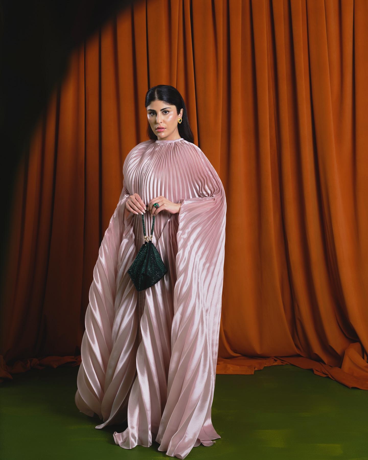 Zaara Al Balushi in a pleated blush gown with an emerald Nine West pouch