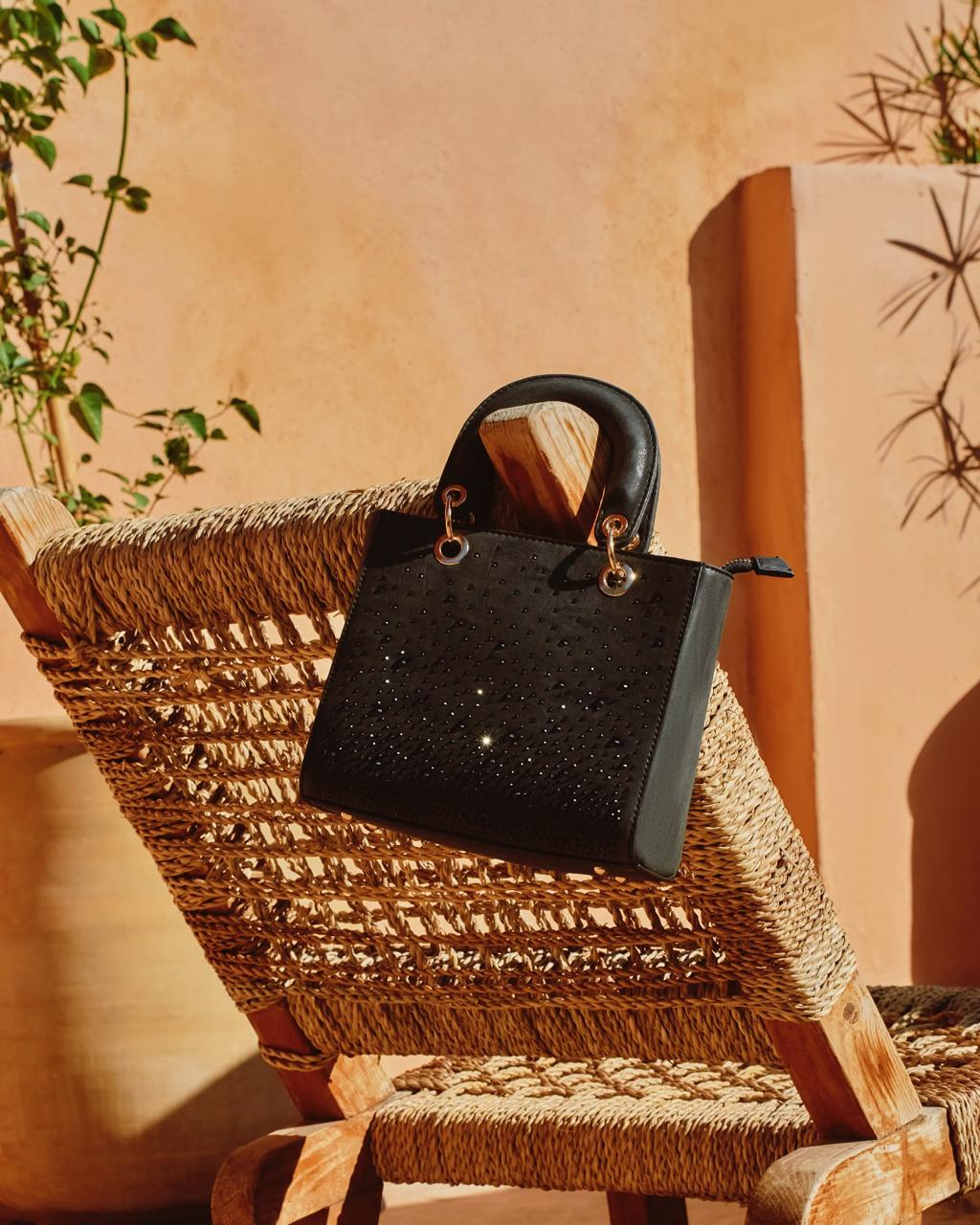 Embellished black handbag on a woven chair