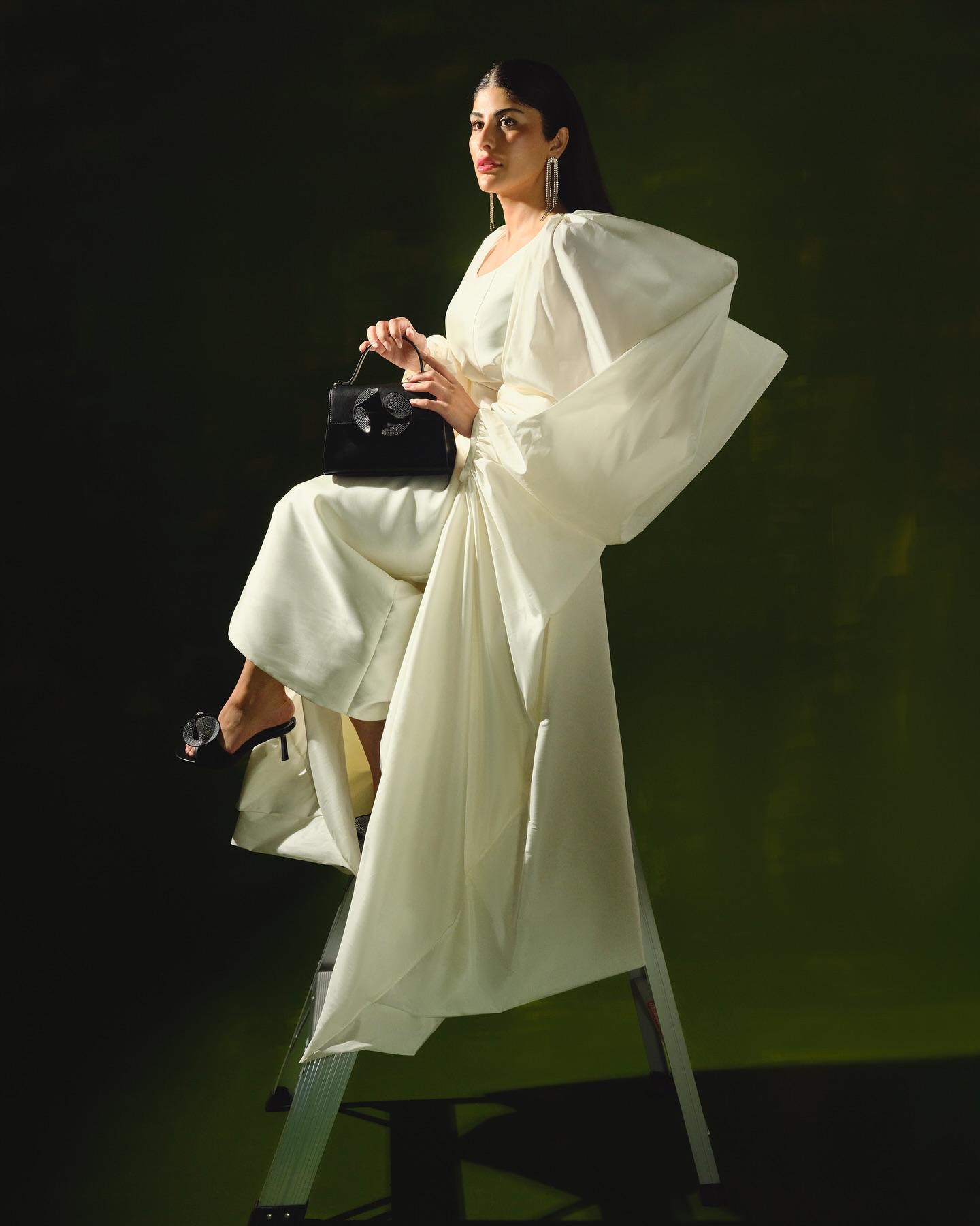 Zaara Al Balushi in an ivory gown holding a black Nine West top-handle bag